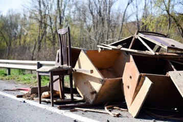 Fototapeta premium Dilapidated wooden debris and a single chair lie scattered on the roadside.