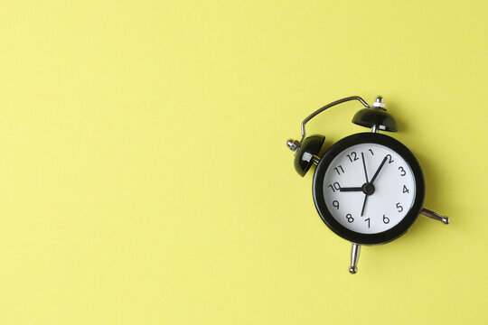 One black alarm clock on pastel background, top view