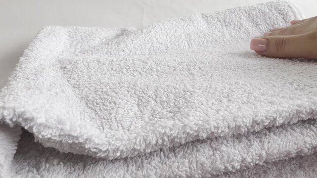 Clean white laundry stack with fresh towels folded perfectly, bathroom spa essentials arranged on table, soft textile care for home comfort.