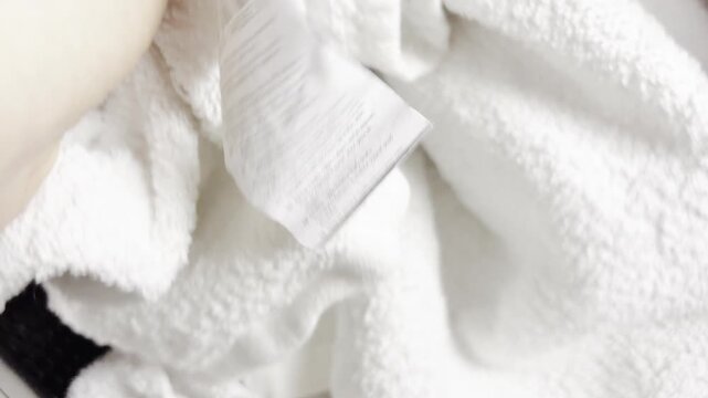 A woman is arranging a stack of clean white towels in the bathroom. Fresh linen neatly folded on a table. Professional home care and laundry services.