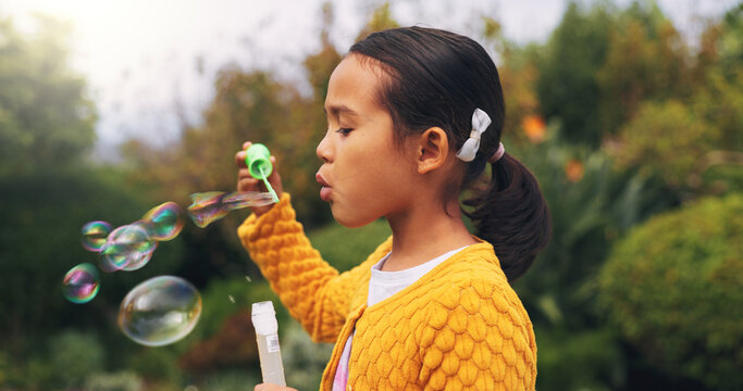 Outdoor, child and blowing bubbles in nature, growth and development with activity on weekend break. Park, entertainment and girl with toy for soap balloons, fine motor skills or playing game for fun