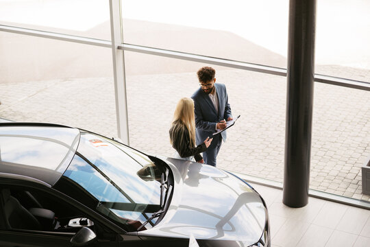 Car salesman assisting woman buying new car