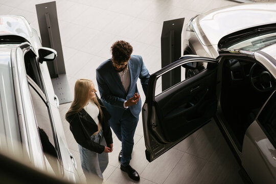 Salesman assisting customer at car dealership showroom