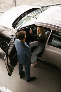 Woman inspecting electric car with salesperson