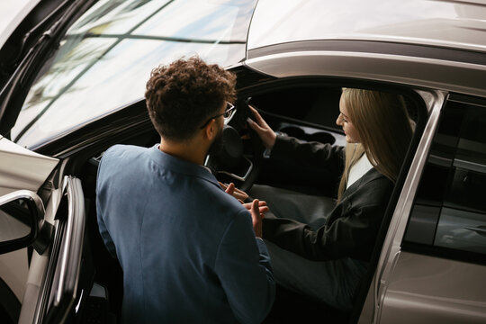 Salesman explaining car features to woman in dealership