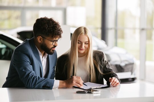 Car salesman assisting customer with purchase agreement details