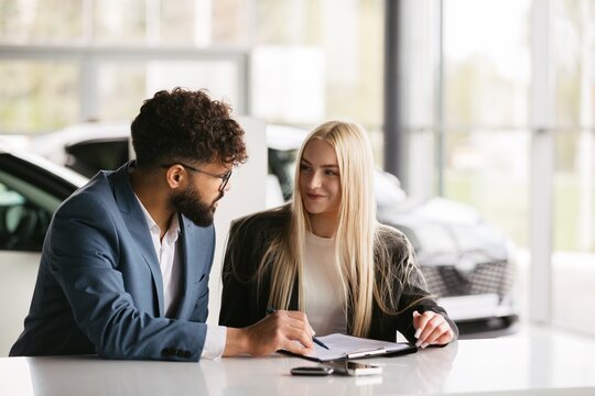 Salesman discussing agreement with client in car dealership