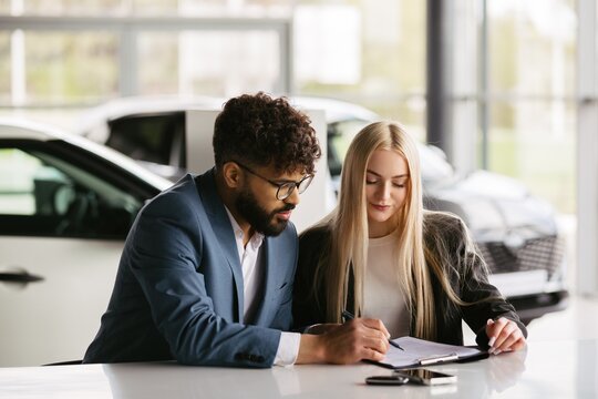 Salesman assisting customer signing car purchase contract