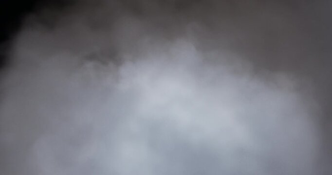 A massive cloud of dense white smoke rises and billows from the bottom of the frame against a pitch-black background, creating a dramatic cinematic effect.
