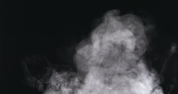 White smoke rises and curls in the air against a deep black background.