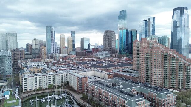 Urban harbor density shows Liberty Landing Marina and surrounding waterfront blocks near Morris Canal Basin with mid rise and high rise forms extending inland. Mixed rooflines, vessel deck, NJ