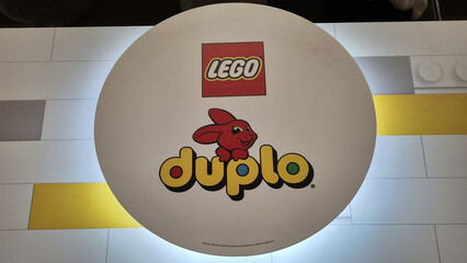 Naklejka premium Red and yellow LEGO and DUPLO logos on a white circular surface featuring a red rabbit mascot over a tiled background. Picture taken on April 27, 2026 in Bucharest, Romania.