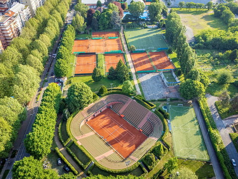 Aerial view of the Circolo della Stampa Sporting sports complex featuring clay tennis courts and a stadium court surrounded by lush green trees in Torino, Piemonte, Italy.