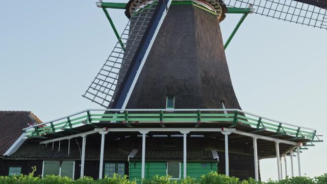 Low angle view of traditional Dutch windmill with rotating blades, historic architecture in Netherlands against sky