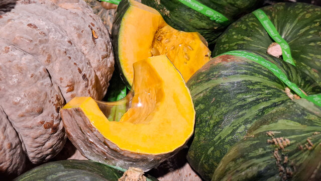 Fresh organic pumpkins whole and sliced with seeds showing at a traditional local market for healthy autumn cooking and nutrition