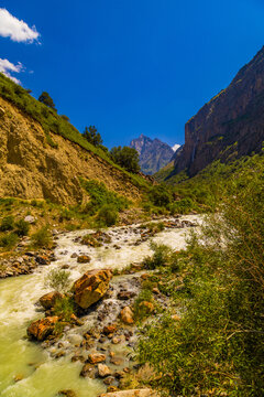 Mountain river flowing through rocky gorge under blue sky