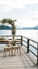 Fototapeta premium Romantic wedding ceremony setup on a wooden dock overlooking a serene lake with mountains and sky