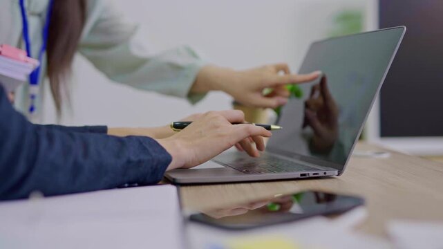 The focused hands typing on a laptop in a modern workspace. 