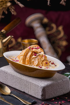 oum ali dish served in an oval bowl topped with an edible rose and cashew nuts