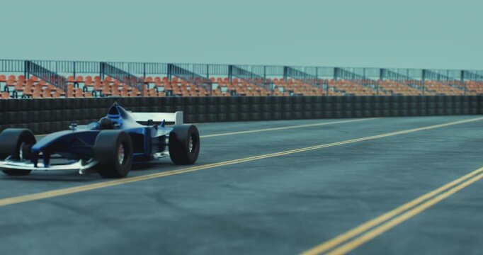 Single-seater race car speeds down a racetrack surrounded by barriers and stadium seating.