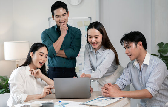 Diverse Asian Business Team Collaborating Around Laptop in Modern Office