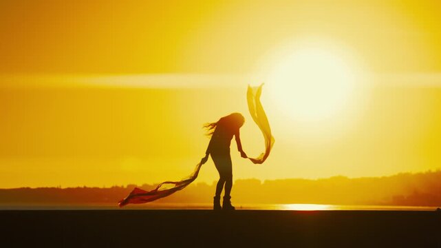 Sunset dance on the beach with colorful scarf in hands