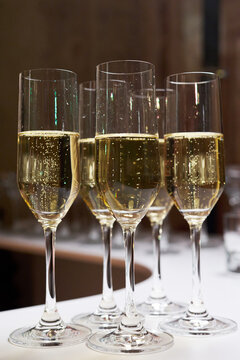Close-up of champagne glasses with bubbles on a white table. Elegant celebration, banquet, or wedding reception scene