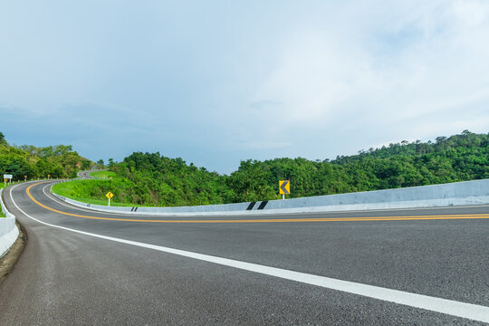 Long curvy forest asphalt road over the hills. Beautiful curved road in the forest. Side view of road.