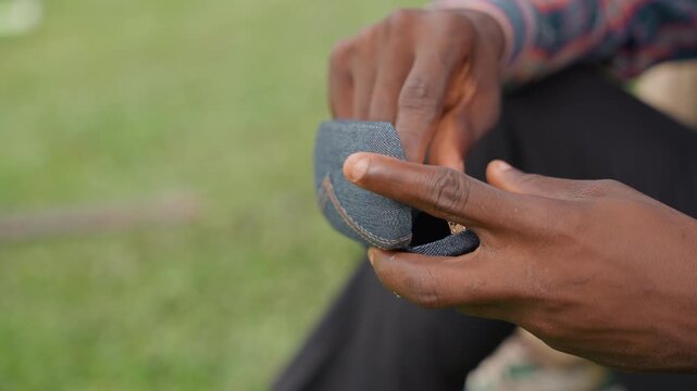 Closeup black father hands cleaning sunglasses with textured case on grass bench, slow careful polish with microfiber cloth, warm afternoon light, intimate bond and focused attention as father tends