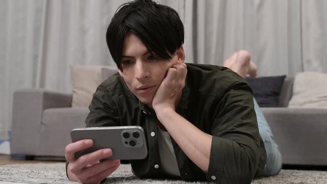 うつ伏せでスマホを見る男性