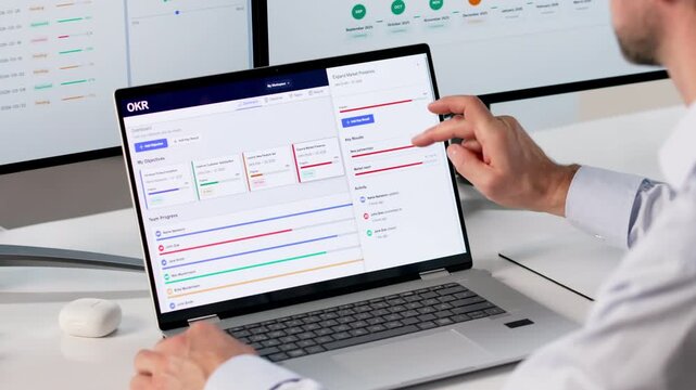 Business Manager Reviews OKR Dashboard On Laptop Tracking Team Performance