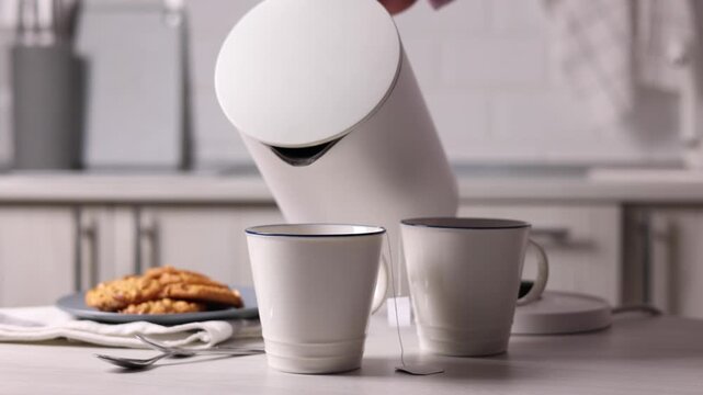 Pure water boils in an electric kettle on the table in the kitchen