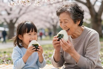 Naklejka premium Japanese grandmother and granddaughter laughing eating onigiri during picnic