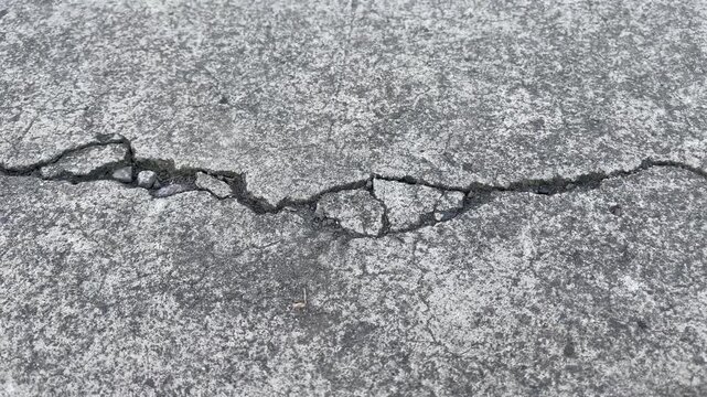 Close-up of cracked asphalt road surface texture