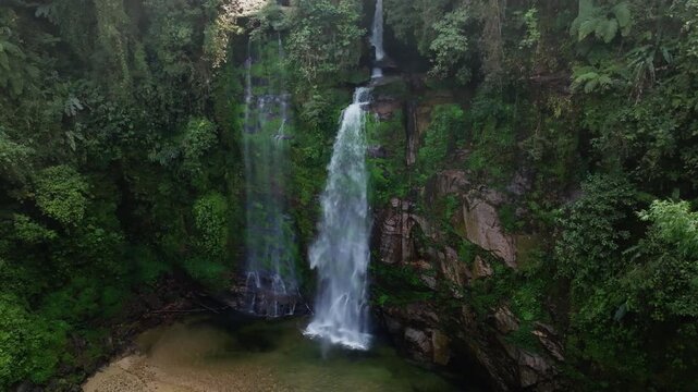Th&aacute;c Ti&ecirc;n waterfall closer aerial view of the main cascade plunging into a calm pool beside rock outcrops, H&agrave; Giang, Vietnam.