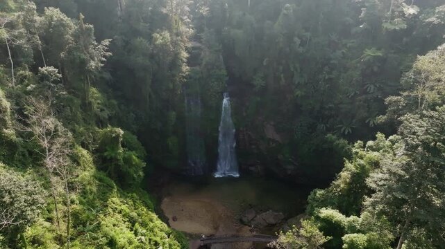 Th&aacute;c Ti&ecirc;n waterfall distant drone shot showing the falls tucked in a dark ravine amid expansive jungle canopy, H&agrave; Giang, Vietnam.