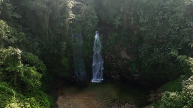 Th&aacute;c Ti&ecirc;n waterfall slow forward drone move revealing cliffside plants, vines, and the bright waterfall column, H&agrave; Giang, Vietnam.