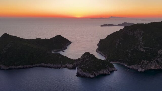 Aerial sunset view over Porto Timoni beach and Afionas peninsula in Corfu, Greece. Stunning double bay coastline with dramatic cliffs and calm Ionian Sea