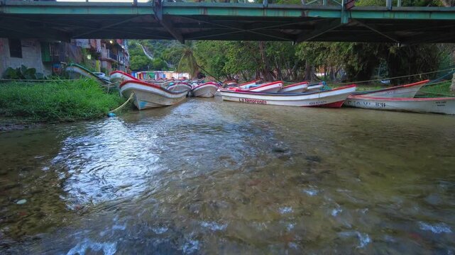 A serene, still view of a flowing river with fishing boats docked together at twilight, at sunrise in the beach town of Choroni, Aragua, Venezuela