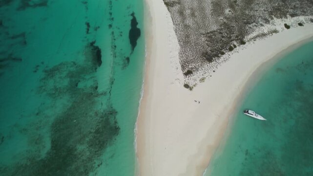 Drone shot Cayo de Agua island, Los Roques, Venezuela. Crystal clear turquoise waters, white sand formations, and speedboat providing scale to the vast, peaceful Caribbean landscape.