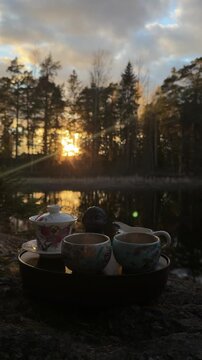 Vertical screen tea ceremony in nature with teaware on chaban in sunset light sun rays creating cinematic spiritual relaxation scene