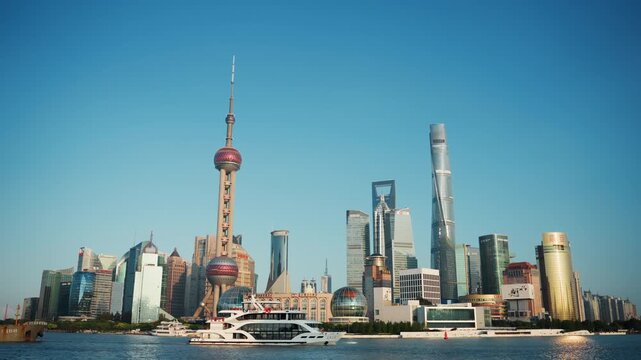 Panoramic shanghai skyline by river, oriental pearl tower center with modern skyscrapers, ferry and yacht traffic on water, sunny clear sky, waterfront reflection and urban energy