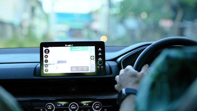 Modern car dashboard displaying digital navigation map and gps route while driving through city streets at sunset.