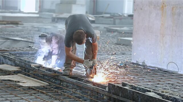 Installation of reinforced concrete floors in a large industrial or commercial building. A team of workers welds metal reinforcement and prepares the building's floors for concrete pouring.