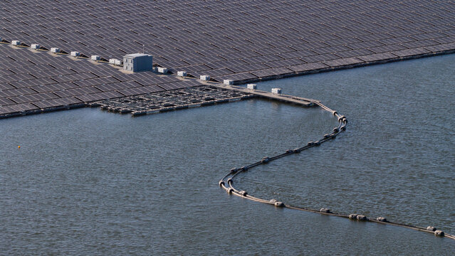 Aerial view of the Bomhofsplas floating solar farm featuring a vast array of photovoltaic panels and a utility building on the water in Zwolle, Overijssel, Netherlands.