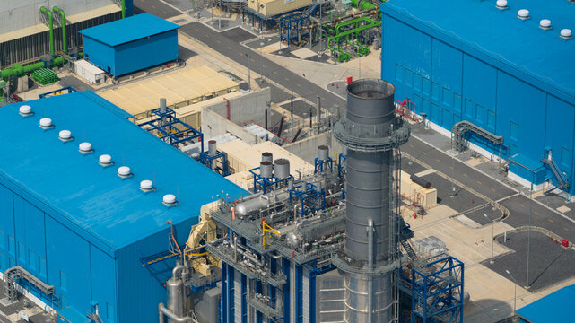 Aerial view of the Sriracha Power Plant GSRC featuring large blue buildings, a tall exhaust stack, and complex piping systems in Tambon Khao Khan Song, Chang Wat Chon Buri, Thailand.
