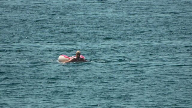 Woman ocean swimming, blonde woman floats peacefully in clear blue water