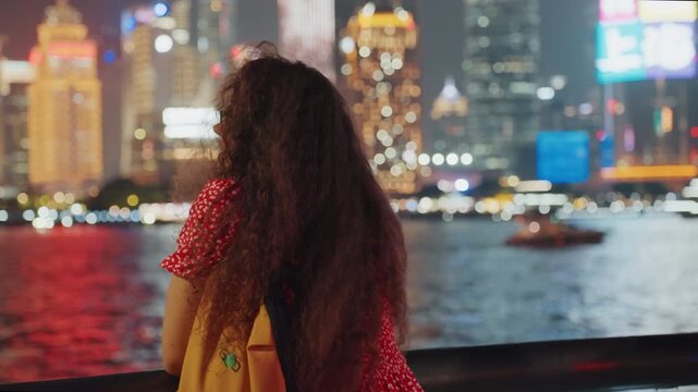 Night riverfront woman back view, waterfront skyline shimmering with colorful lights, woman leaning on railing, backpack visible, city reflections on water, contemplative silhouette, slow boat