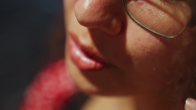 Close up lips and glasses whispering softly, intimate portrait speaker wearing green rim glasses and red scarf, skin texture glowing under warm cinematic light, slow mouth movements and subtle smile,
