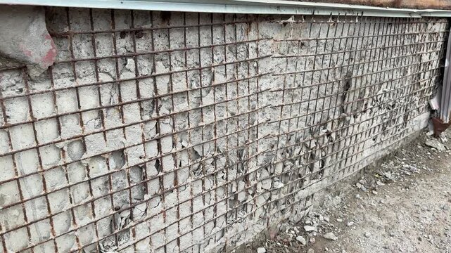 Rusty metal mesh on apartment extension showing heavy corrosion, flaking exposed brick, twisted mesh.